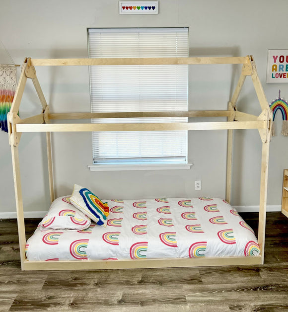 Wooden house bed with rainbow bedding in a bright child bedroom